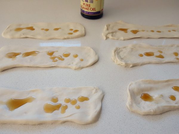 Kneaded dough cut into smaller sections and flattened, then rubbed with sesame oil