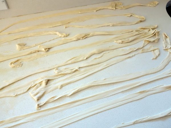Stretching and thwacking dough against counter yields incredibly long noodles